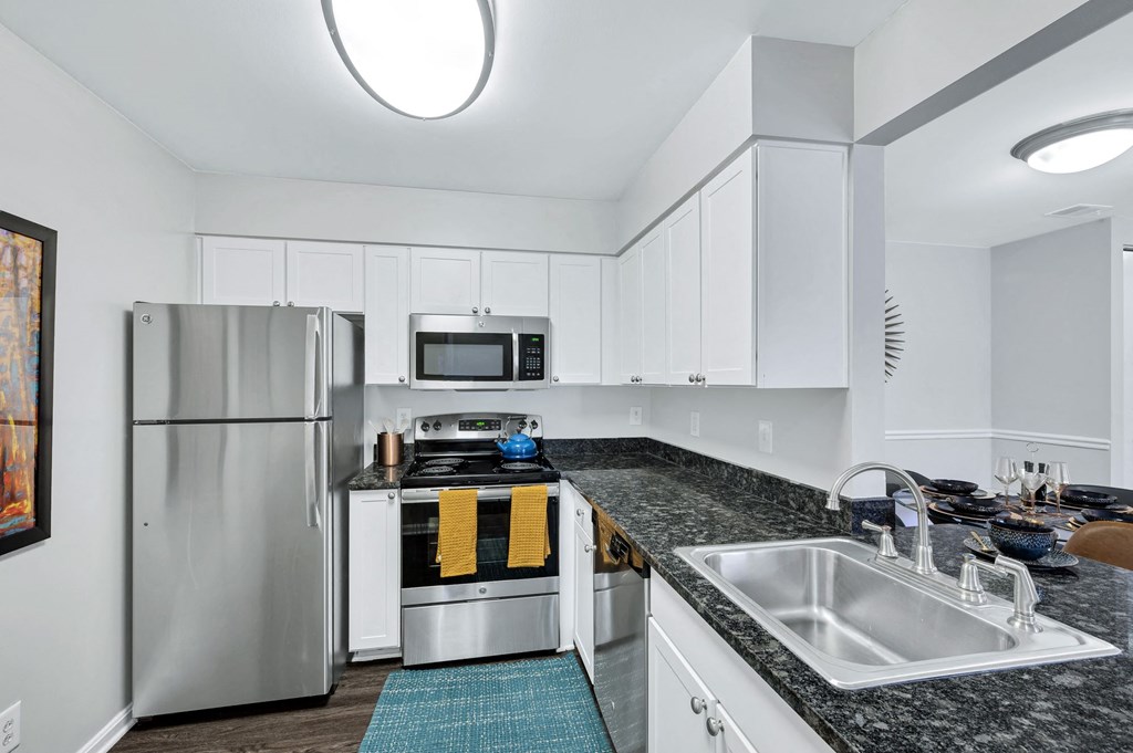 Renovated kitchen at Waterside at Reston with white cabinets, granite countertops and stainless steel appliances.