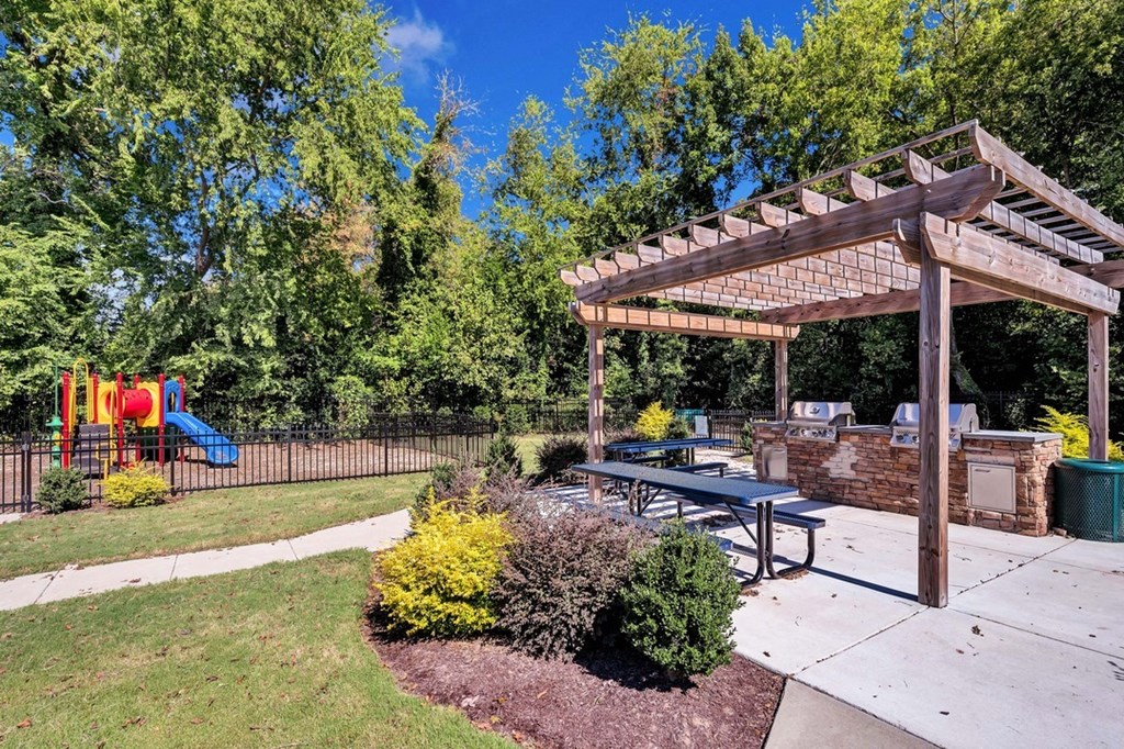 a patio with a picnic table and a playground in the background