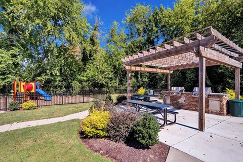 a patio with a picnic table and a playground in the background