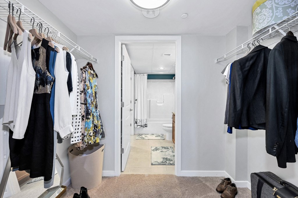 a walk in closet with clothes hanging on a rack and a door to a bathroom