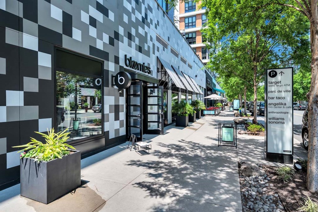 a sidewalk in front of a store with trees and a building