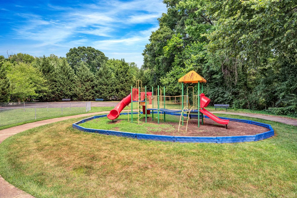 a playground with a blue trampoline and red slides