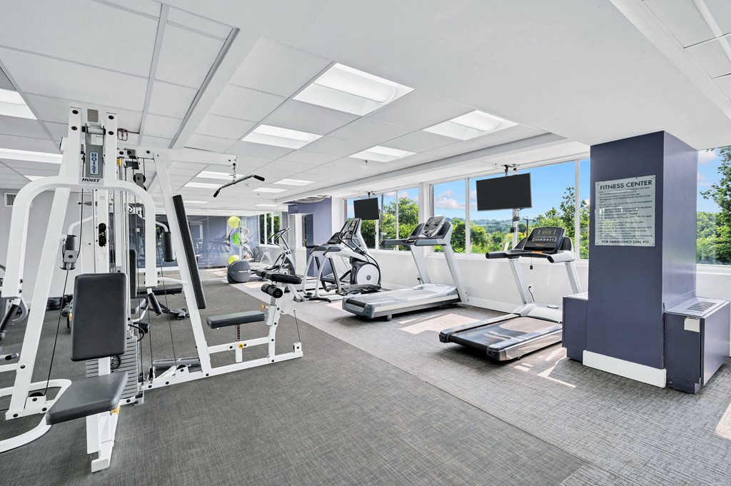 a gym with treadmills and other exercise equipment in a room with windows