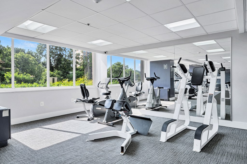 a gym with various cardio machines and windows in a building