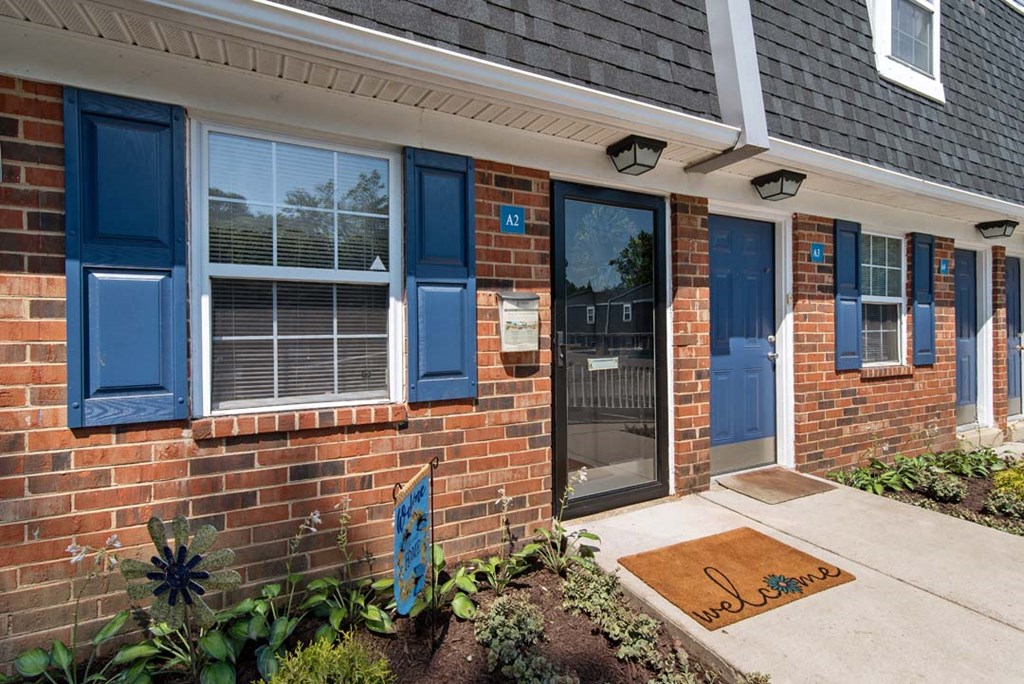 a front porch of a brick house with blue shutters