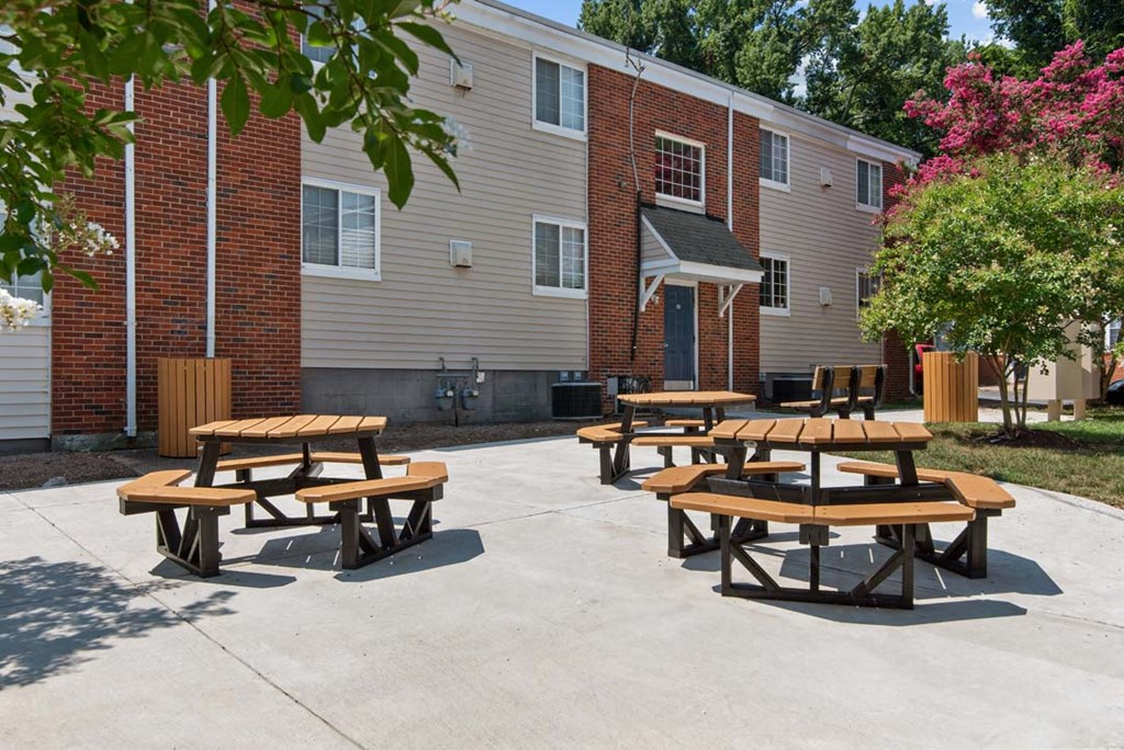 a patio with two picnic tables and a brick building