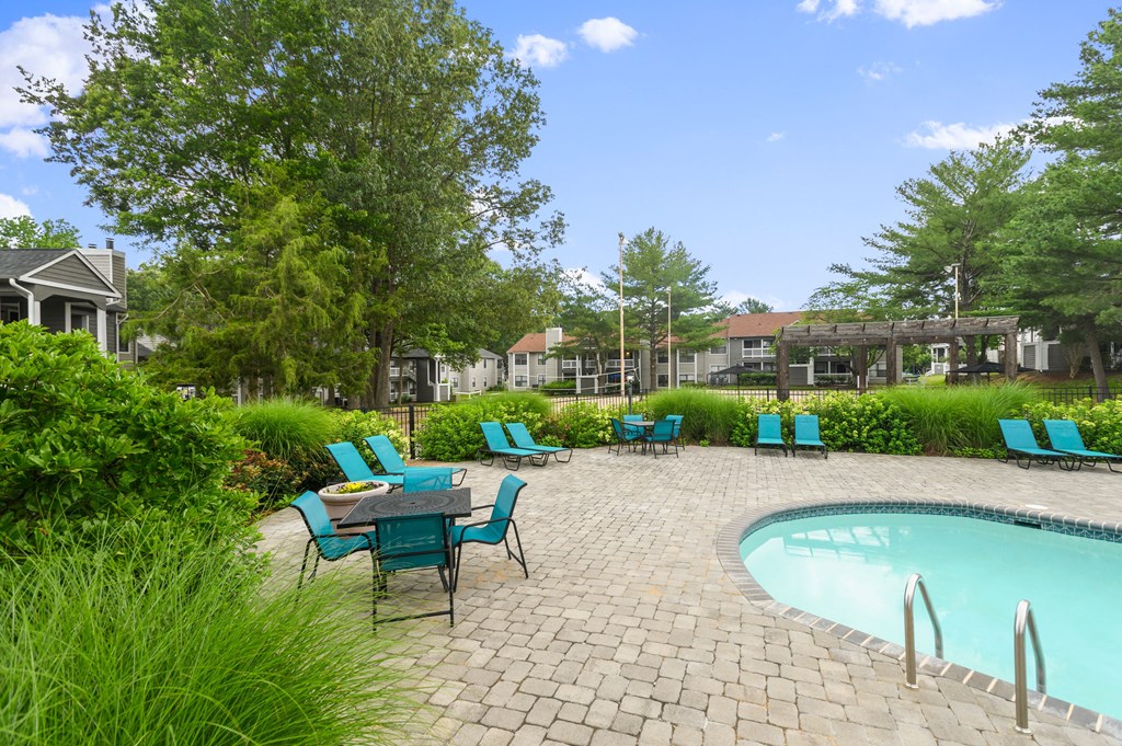 a swimming pool with blue chairs and a patio with a table and chairs