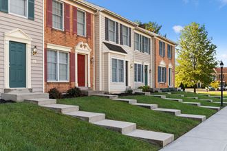 a row of townhomes with green grass and a sidewalk