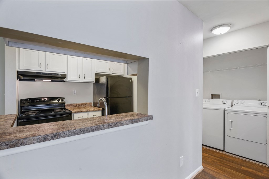a kitchen with white cabinets and a counter top and a stove and refrigerator
