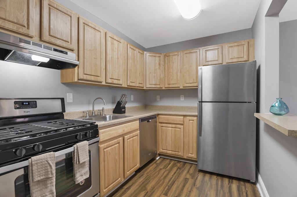 A kitchen with wooden cabinets and a stainless steel refrigerator.