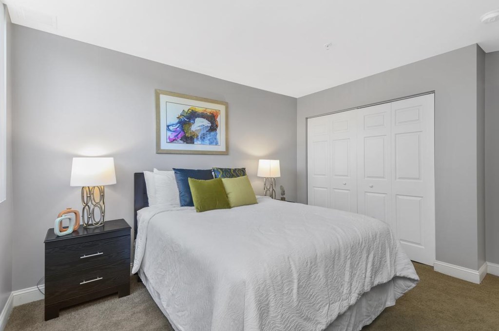 A bedroom with a bed, nightstands, and a painting on the wall.