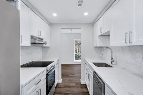 a white kitchen with white cabinets and a sink