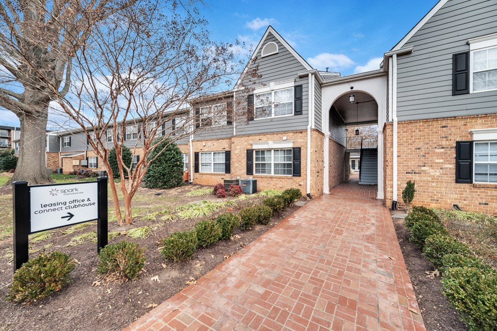 an apartment building with a brick walkway and a sign in front