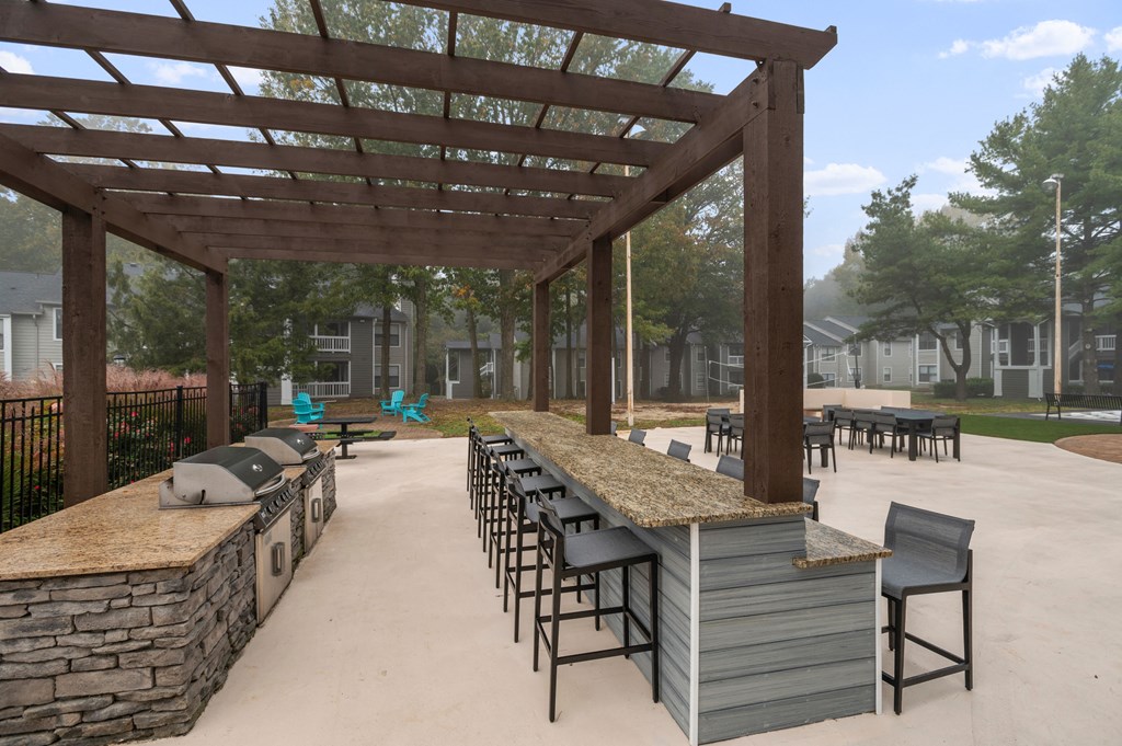 a patio with a bar and tables under a wooden structure