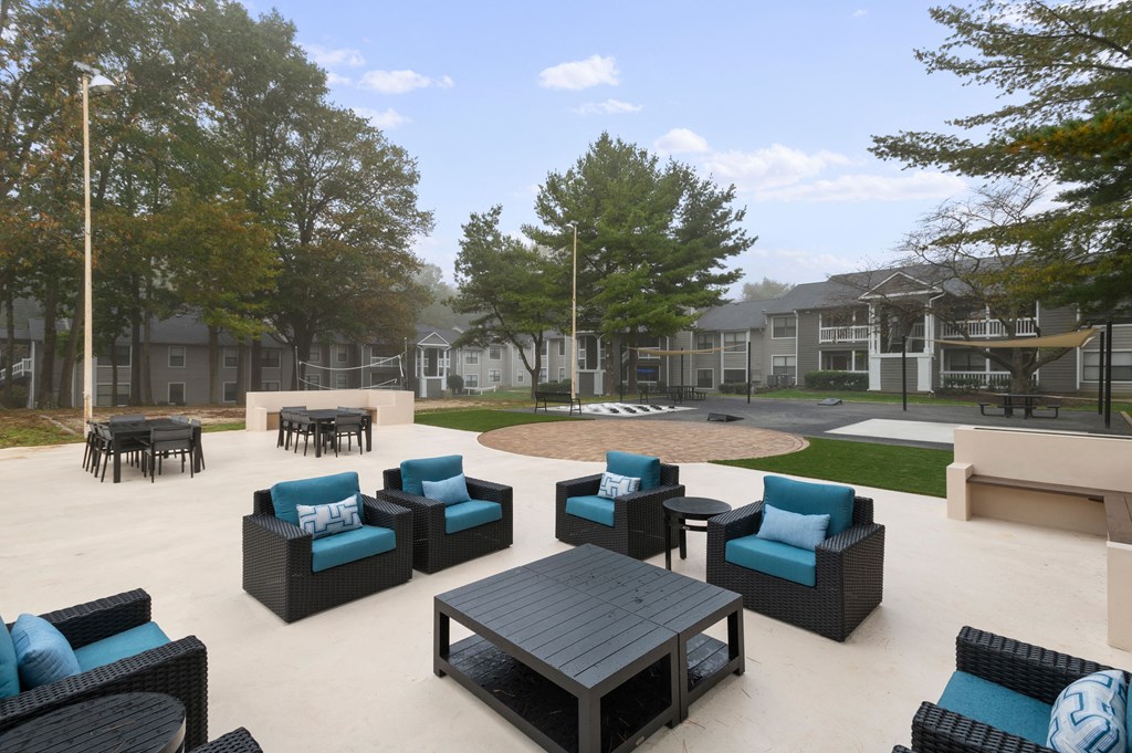 an outdoor patio area with blue chairs and tables and a fire pit