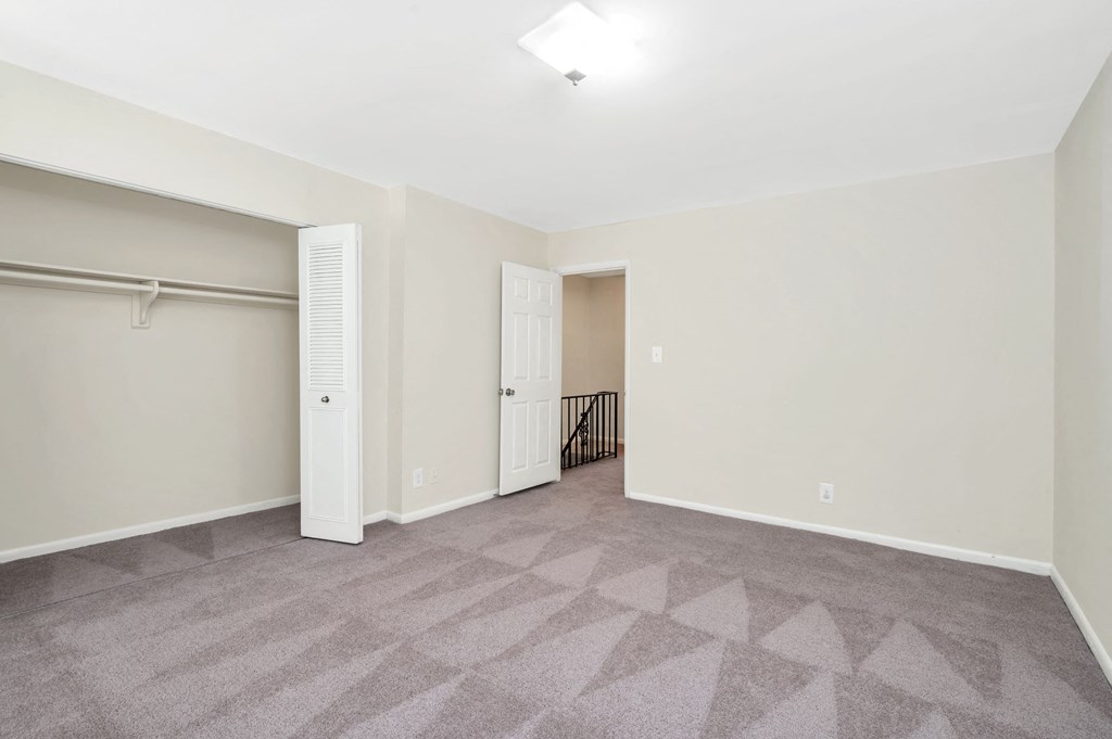 a living room with carpet and a door to a closet