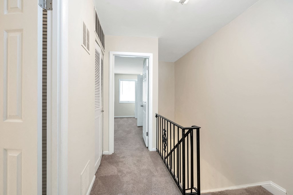 a hallway with a staircase and a door to a bedroom and a closet and a