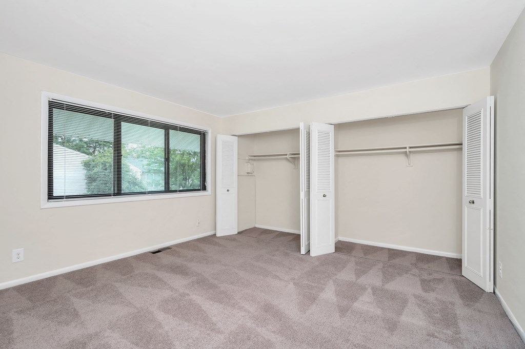 an empty bedroom with a window and a closet