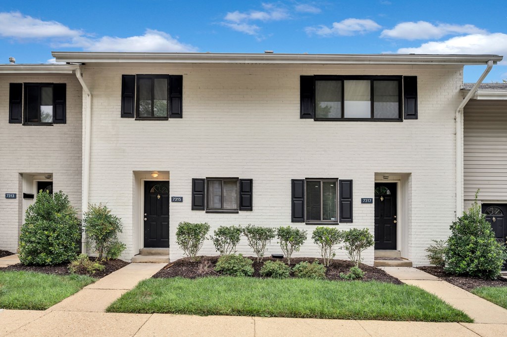 the front of a white house with black shutters and a sidewalk
