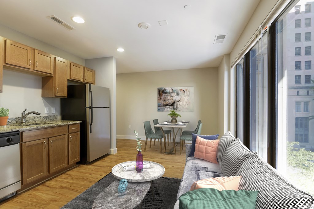 a living room with a couch and a table and a kitchen with a large window