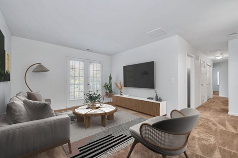 a living room with a couch and chairs and a tv on the wall
