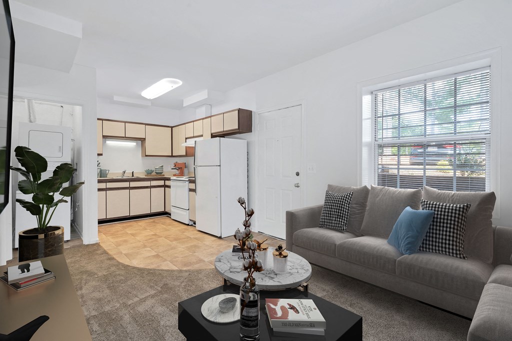 a living room with a couch and a coffee table and a kitchen