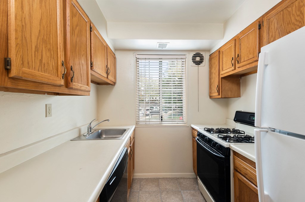 a kitchen with wood cabinets and white appliances and a window