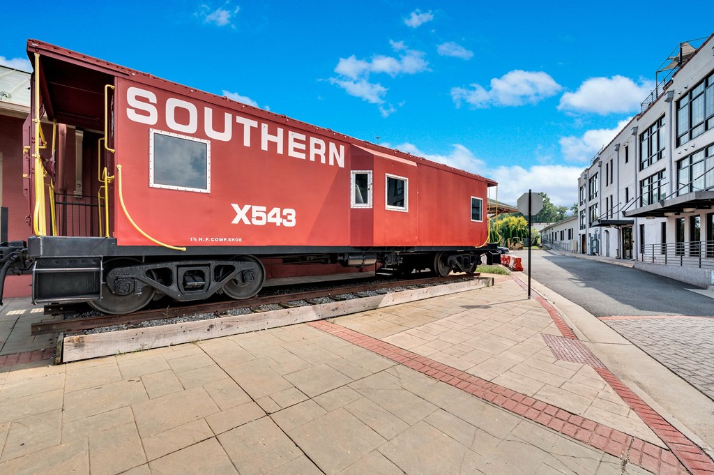 a red train car parked on the tracks next to a sidewalk