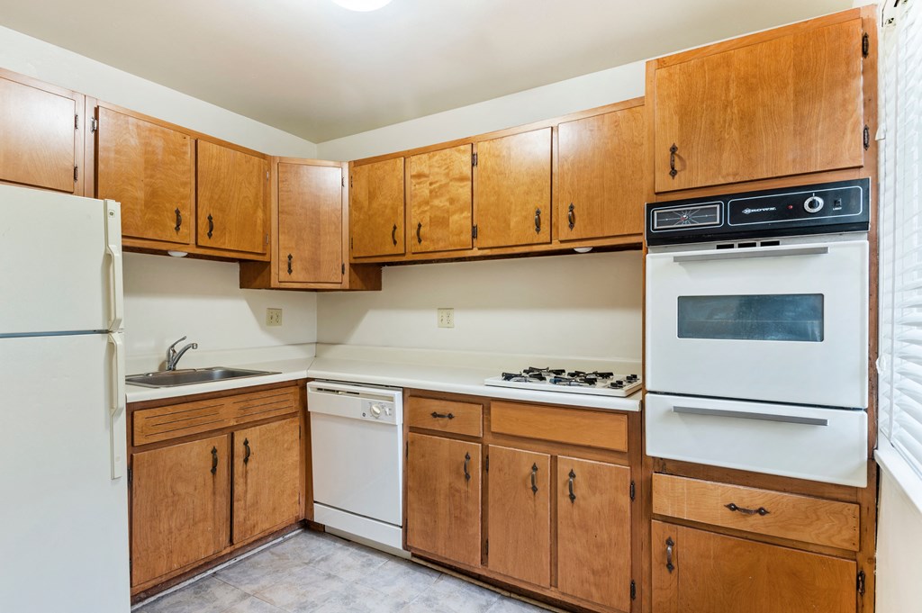 an empty kitchen with wooden cabinets and white appliances