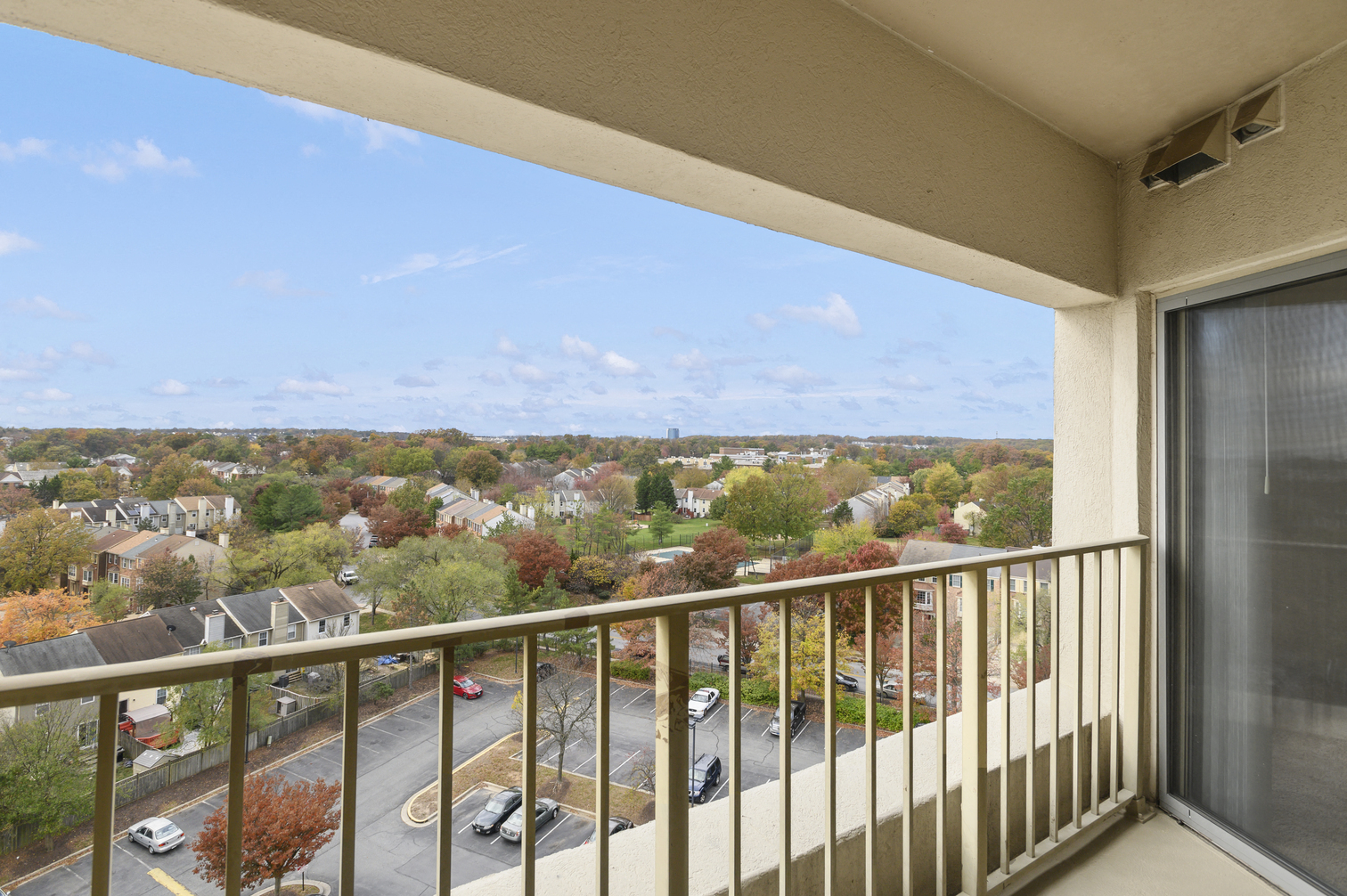 a balcony with a view of a parking lot and trees