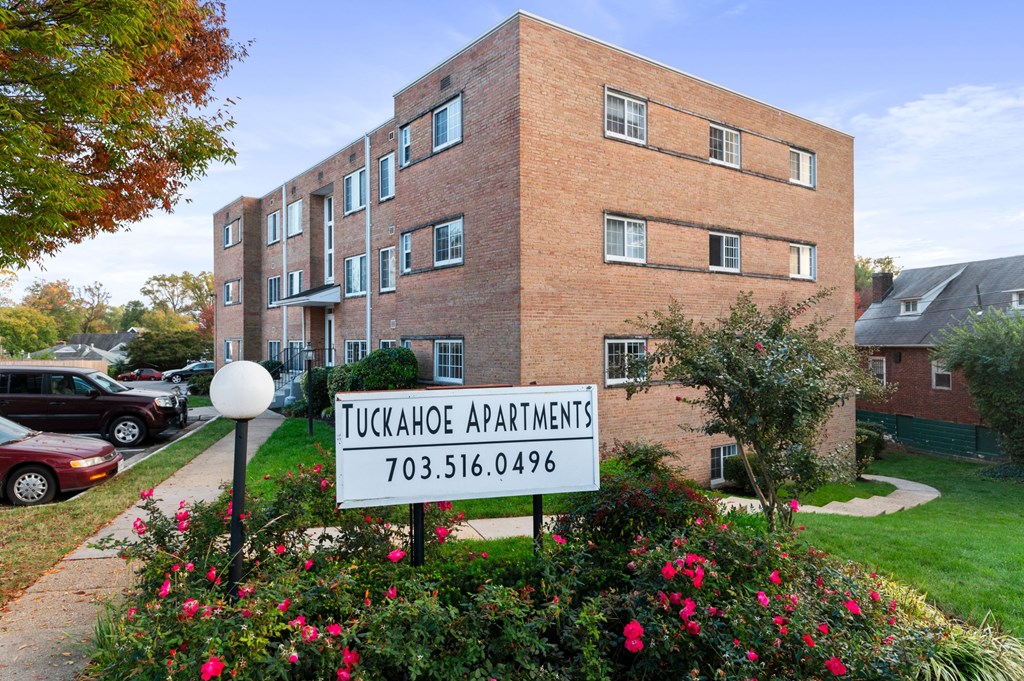 an apartment building with a sign in front of a garden