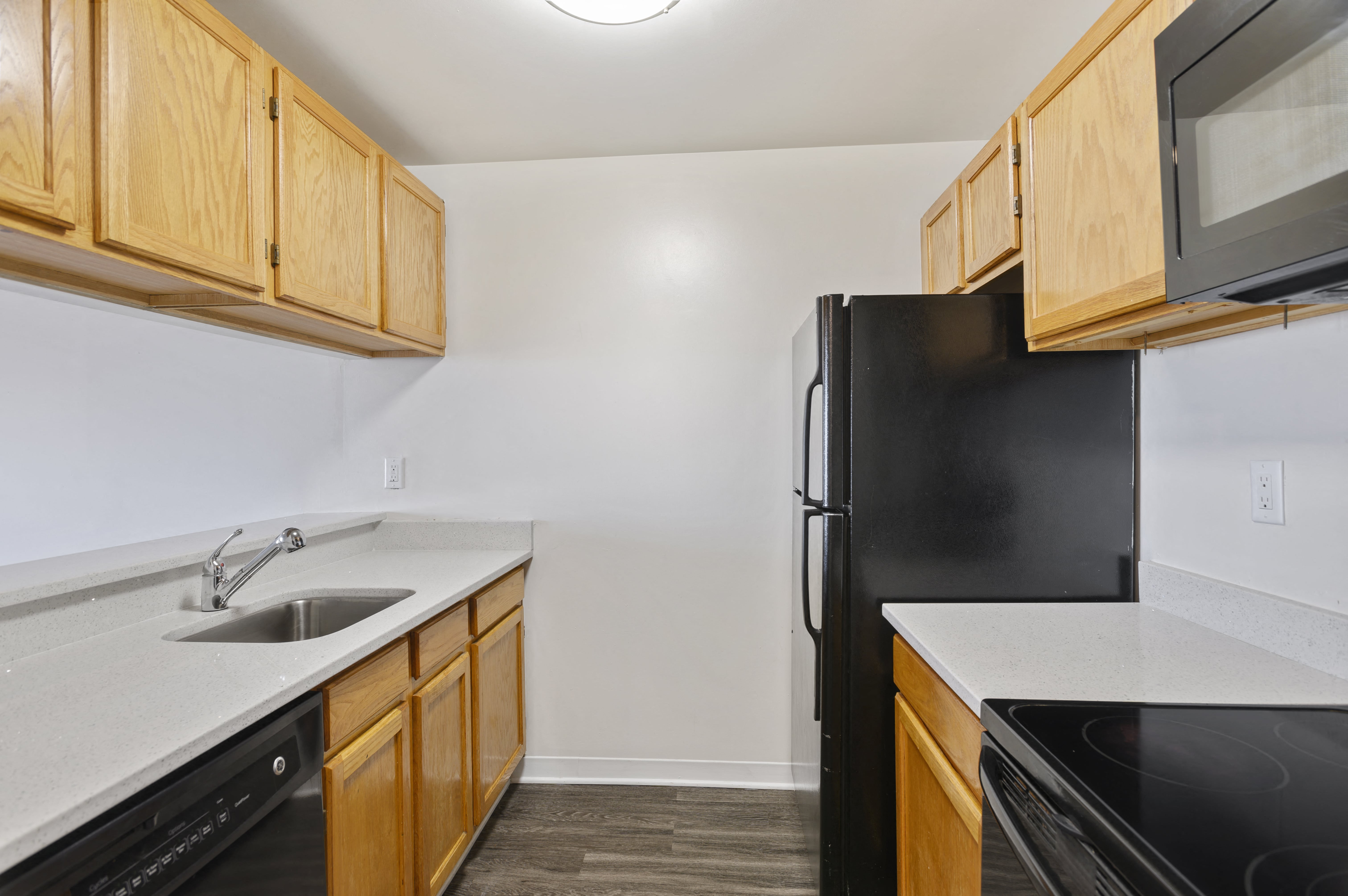 an empty kitchen with black appliances and wood cabinets