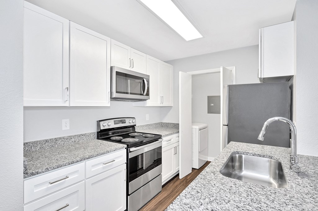 a renovated kitchen with granite counter tops and white cabinets