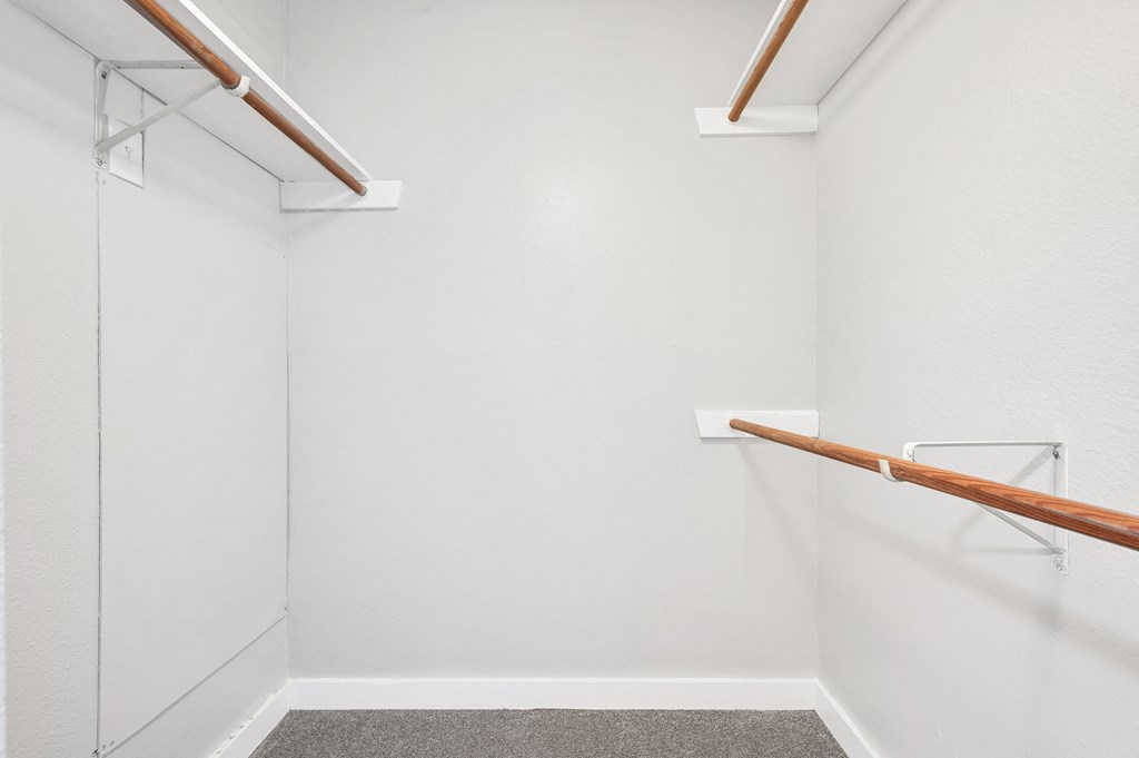 a walk in closet with white walls and a glass door