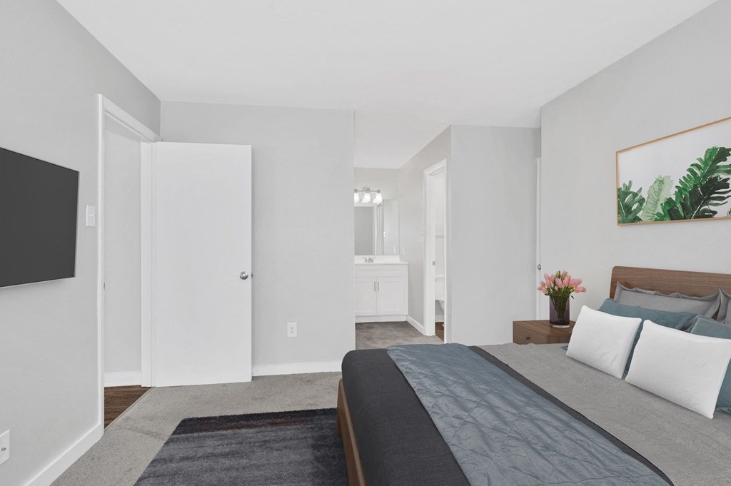 a bedroom with a large bed and a bathroom in the background