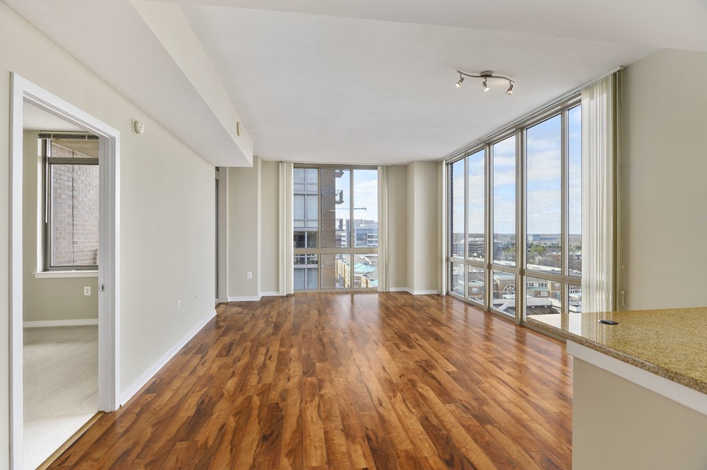 an empty living room with wood flooring and large windows