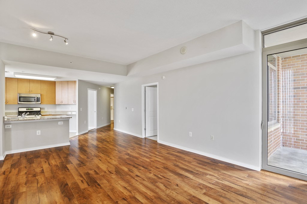 an empty living room and kitchen with wood flooring and a window
