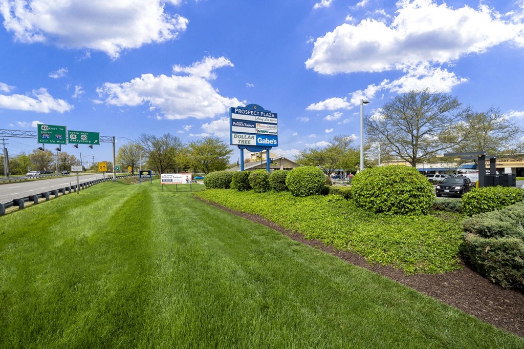 a parking lot with a green lawn and a highway sign