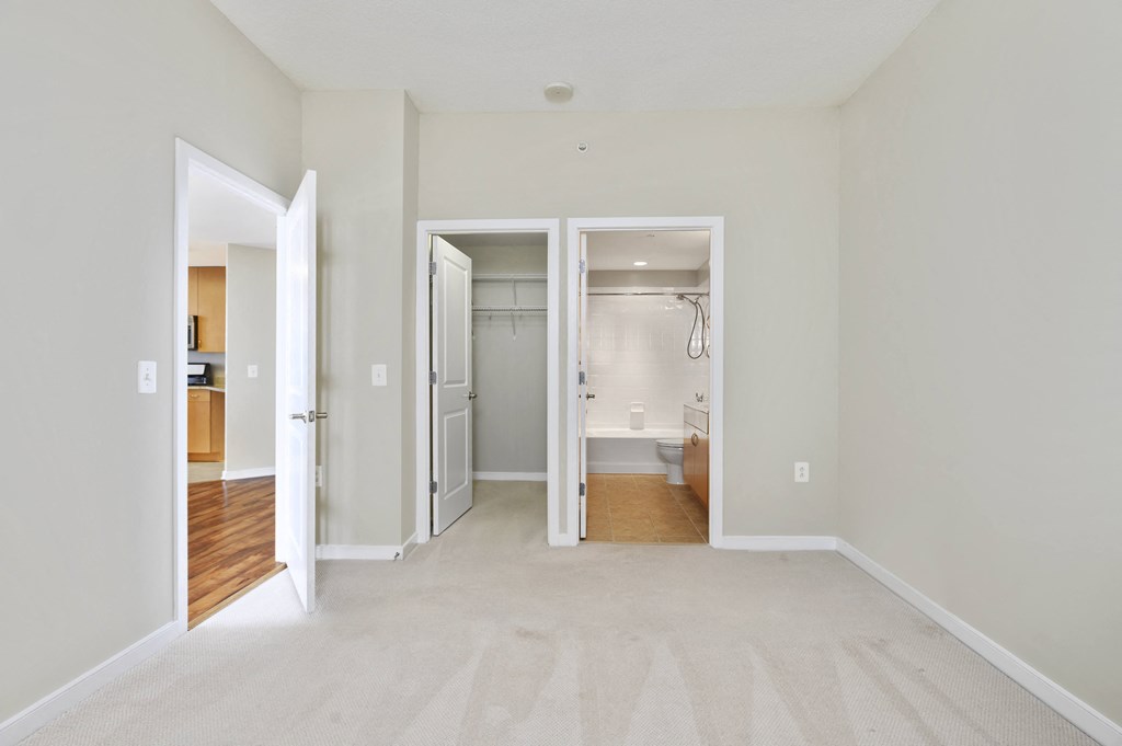 an empty living room with two open doors to a bathroom and a closet