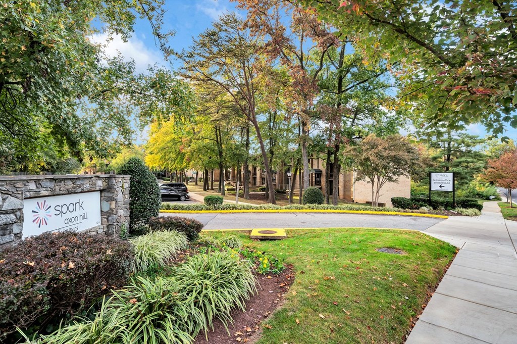 a stone wall with a sign in front of a building with trees in the background