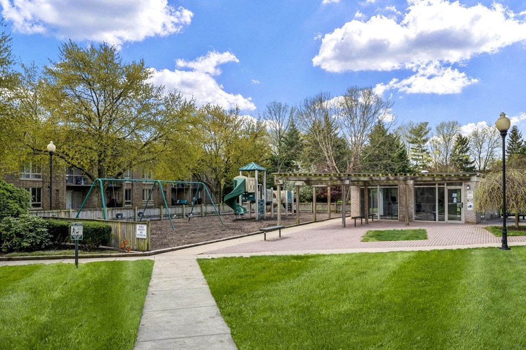 a playground in a park with trees and a building