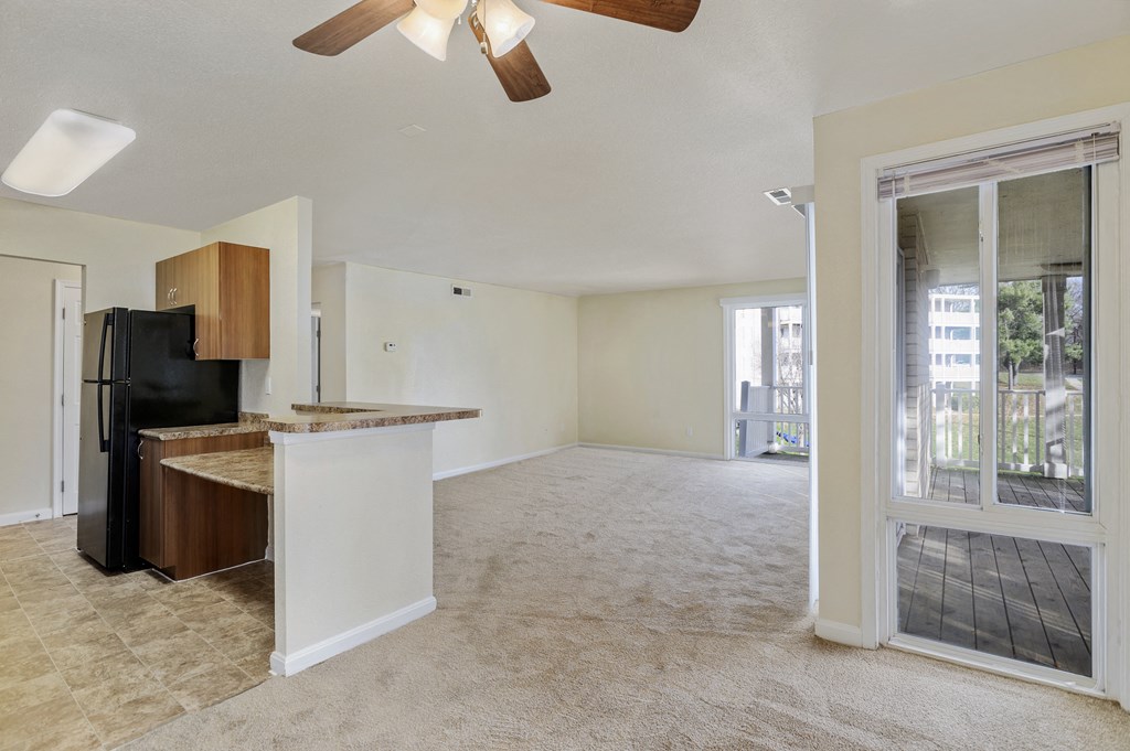 an empty living room and kitchen with a door to a balcony