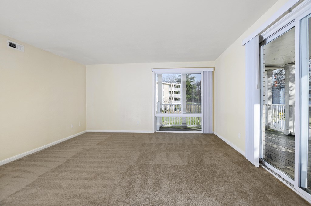 a living room with carpet and sliding glass doors to a balcony
