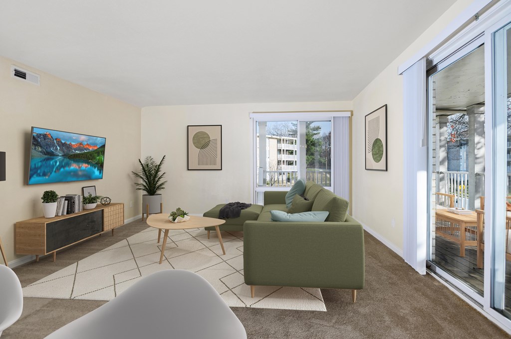 A living room with a green couch, a wooden table, and a painting on the wall.