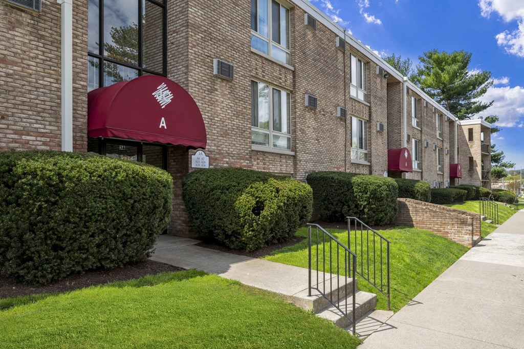 an apartment building with a red awning and a sidewalk in front