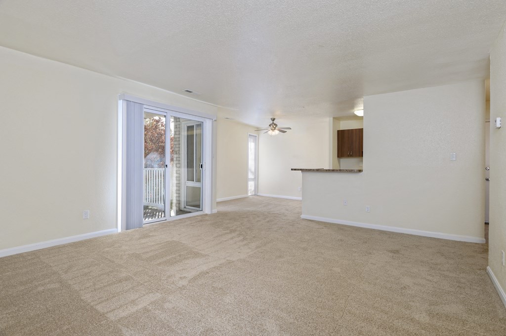 an empty living room with a door to a balcony