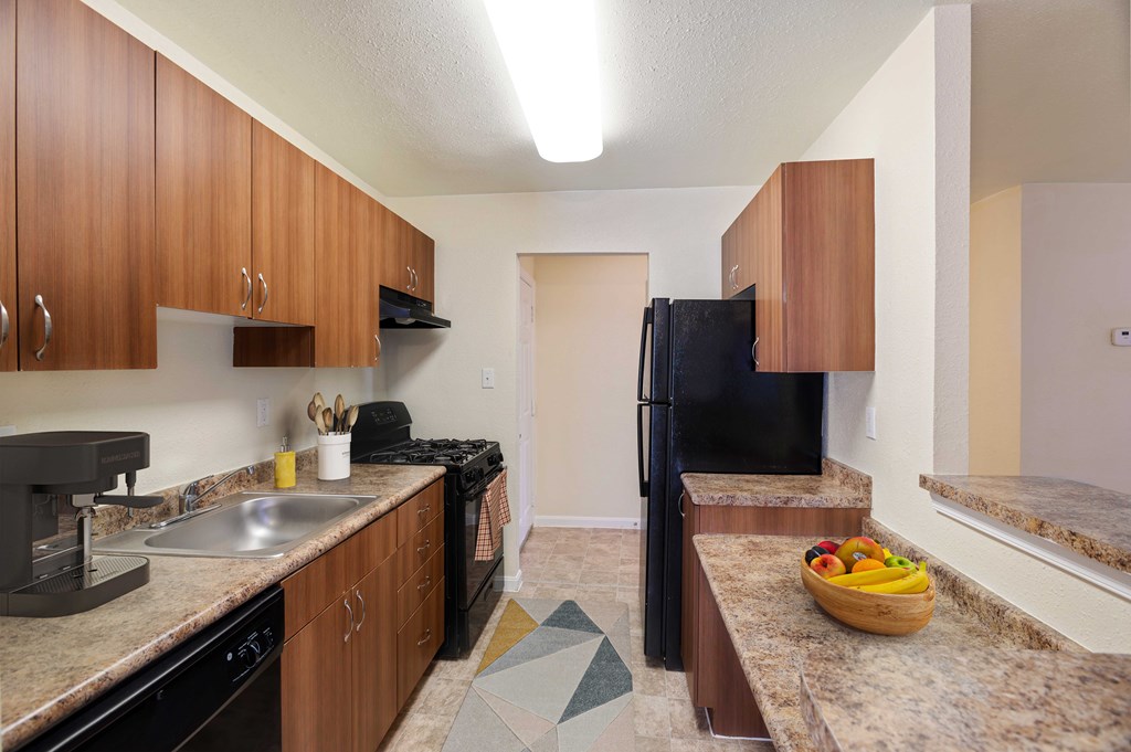 A kitchen with brown cabinets and black appliances.