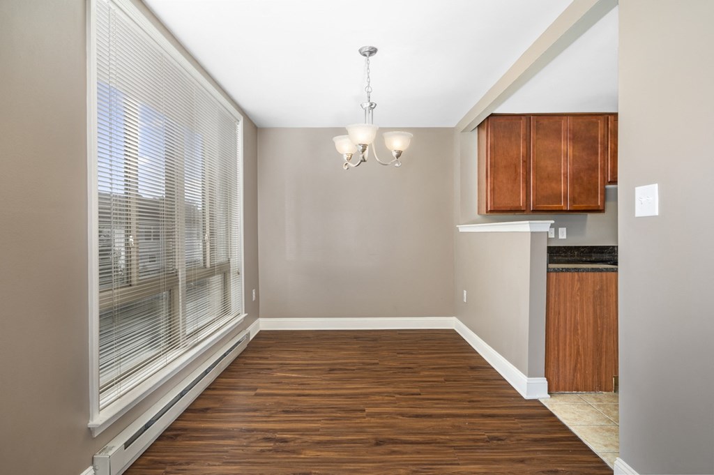 an empty living room with large windows and a kitchen