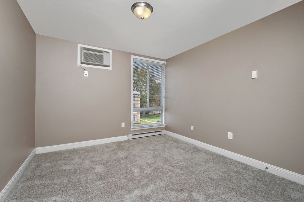 an empty living room with a window and carpet