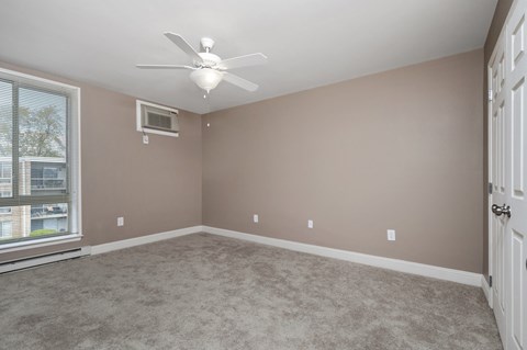 an empty bedroom with a ceiling fan and a window
